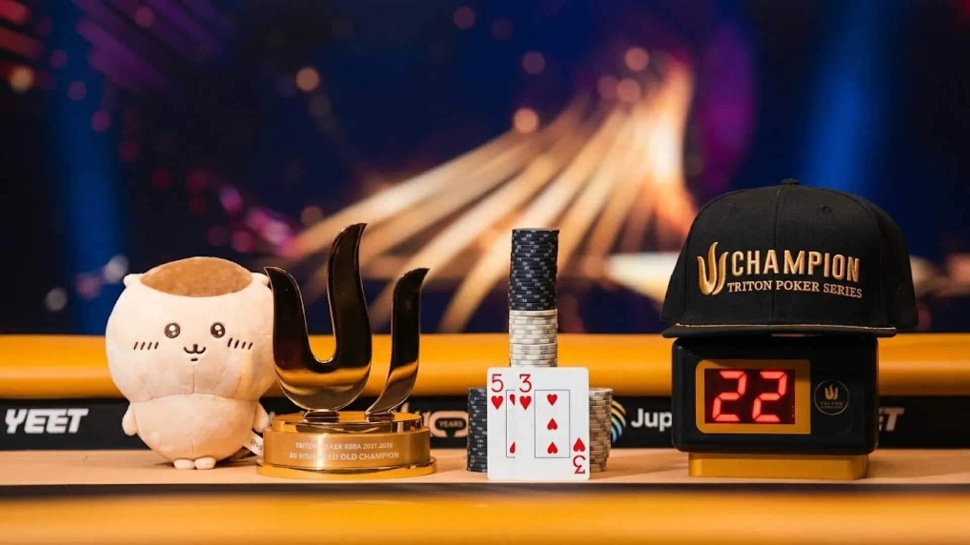 2026年済州大会ファイナルテーブルに並ぶTriton Poker Seriesチャンピオンキャップ、金のトライデントトロフィー、チップ、そして勝利を決めた5-3のカード