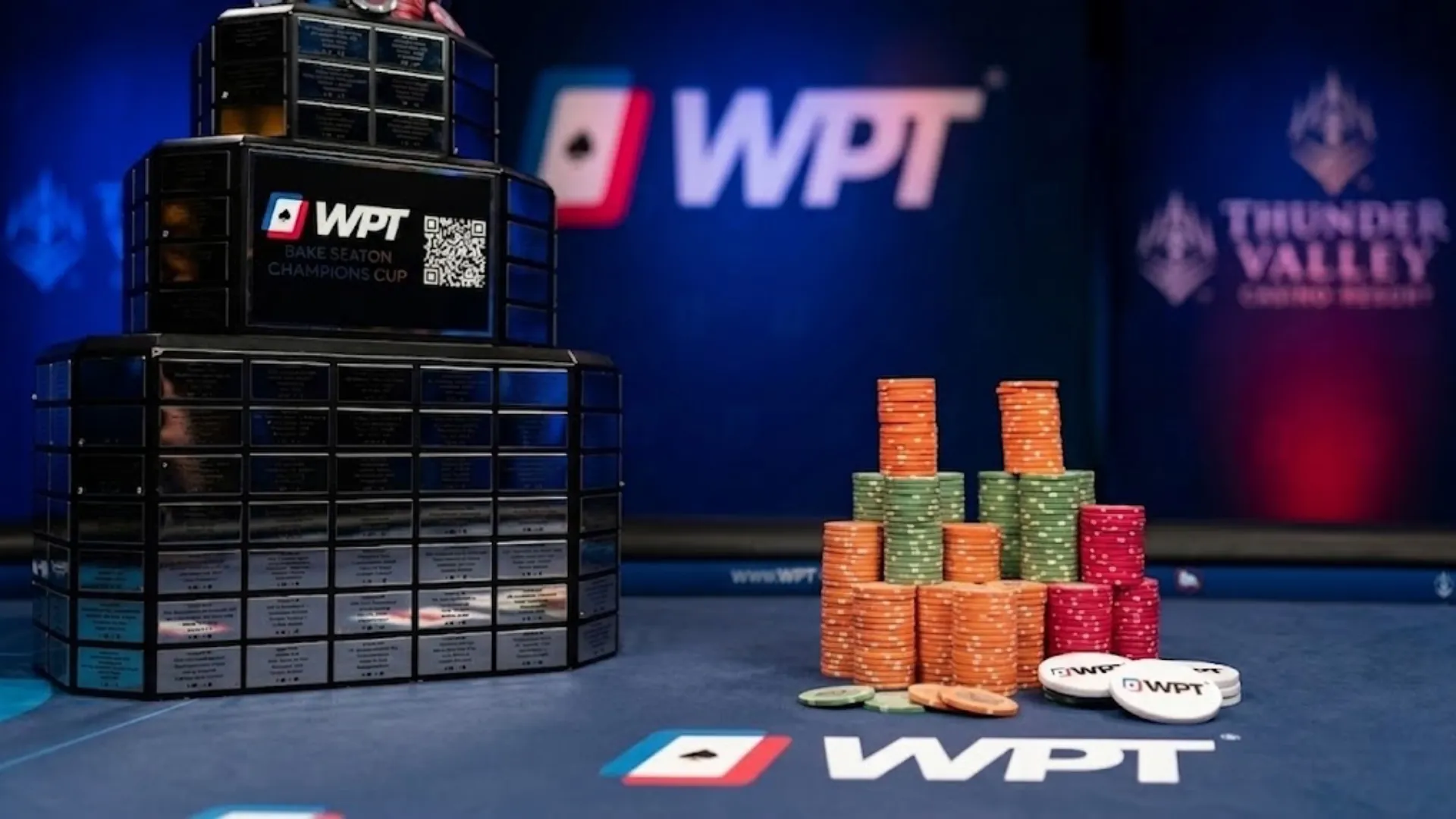 A male poker player smiling, celebrating with the multi-tiered World Poker Tour (WPT) Champions Cup trophy at Thunder Valley Casino, showing a flush with Ace and Nine of Hearts. Poker chips are in front.